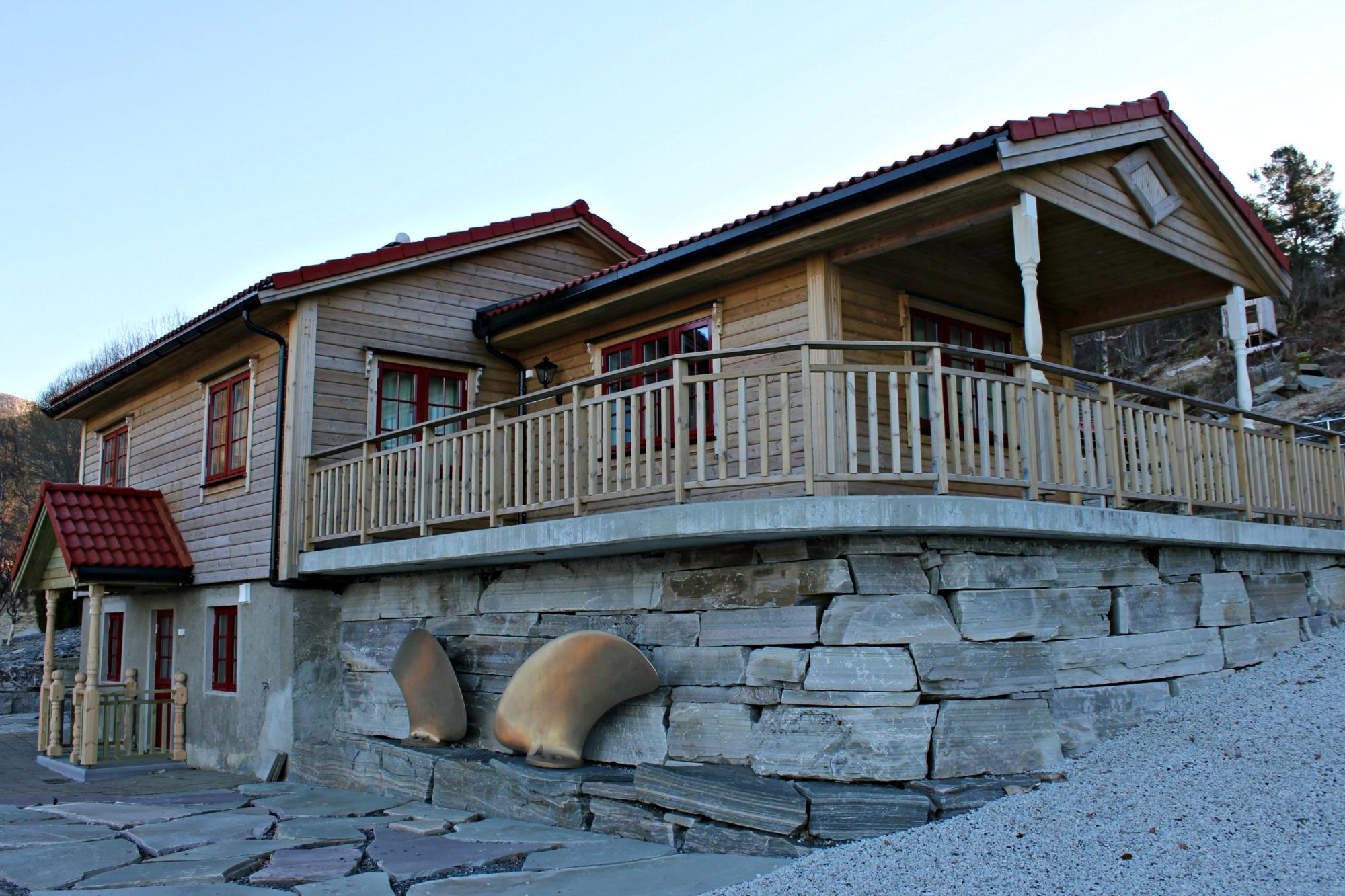 A new timber house with a wide veranda, standing on a foundation wall of large stones