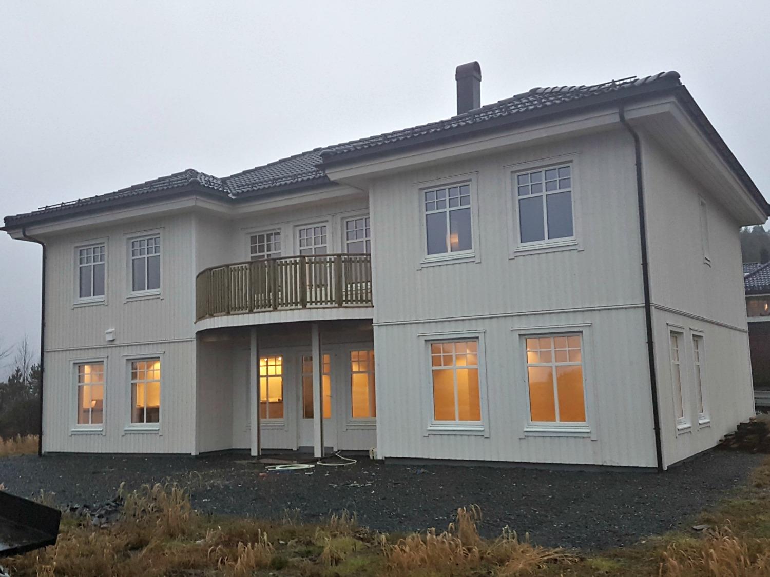 A new two-storey house with a balcony, lights on inside