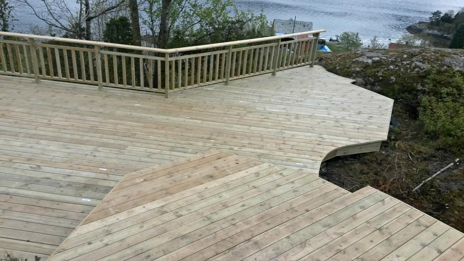 A new wooden terrace with a railing, built around a rocky slope